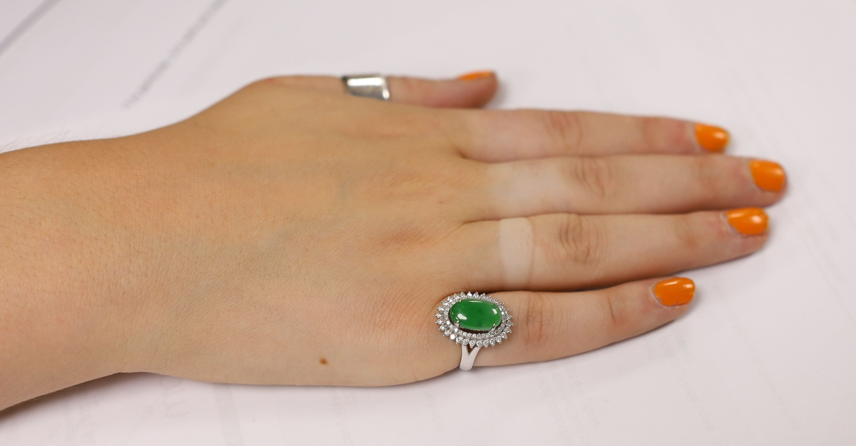 A modern 18k white metal, cabochon jade and two row diamond chip set oval cluster ring size L, gross weight 6.4 grams.